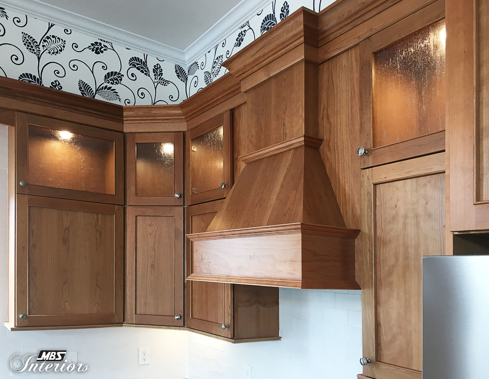 Example of a mid-sized transitional l-shaped dark wood floor and brown floor eat-in kitchen design with an undermount sink, recessed-panel cabinets, medium tone wood cabinets, granite countertops, white backsplash, ceramic backsplash, stainless steel appliances and an island