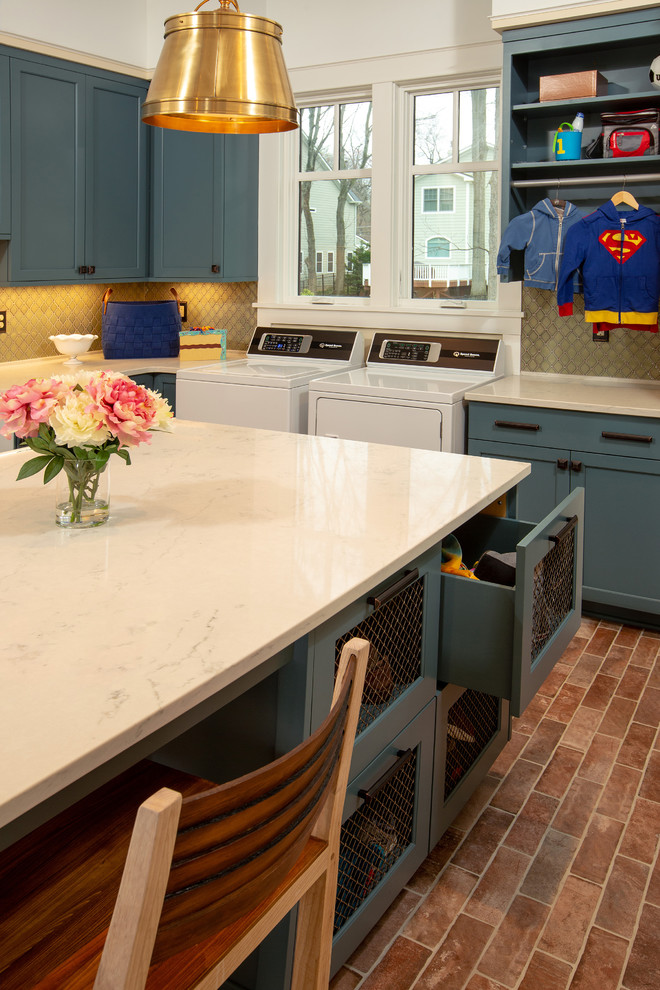 Large traditional l-shaped dedicated laundry room in DC Metro with a farmhouse sink, shaker cabinets, blue cabinets, quartz benchtops, yellow walls, porcelain floors, a side-by-side washer and dryer, red floor and white benchtop.