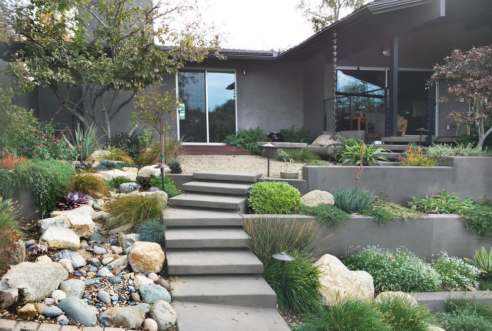 Small midcentury courtyard xeriscape in Los Angeles with a retaining wall and gravel.