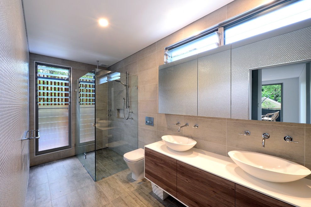 Contemporary bathroom in Sydney with flat-panel cabinets, medium wood cabinets, a curbless shower, a one-piece toilet, gray tile, grey walls, a vessel sink and a hinged shower door.