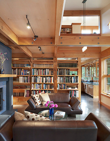 Photo of a large contemporary open concept living room in Portland Maine with a library, concrete floors and a standard fireplace.