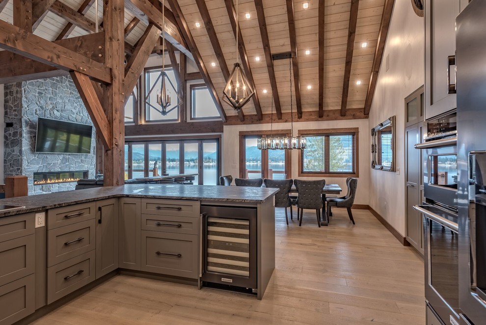 Large arts and crafts u-shaped open plan kitchen in Other with an undermount sink, shaker cabinets, brown cabinets, stainless steel appliances, light hardwood floors, a peninsula and beige floor.