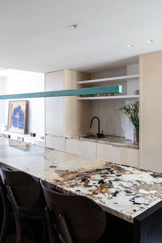 Inspiration pour cuisine ouverte in U and bois clair With un évier intégré, un placard à porte plane, un plan de travail en quartz, une crédence blanche, une crédence en céramique, un électroménager noir, un sol en carrelage de céramique, îlot, un sol beige and un plan de travail beige.
