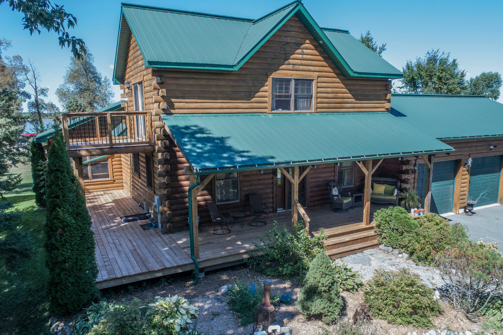 Example of a huge mountain style backyard deck design with a roof extension