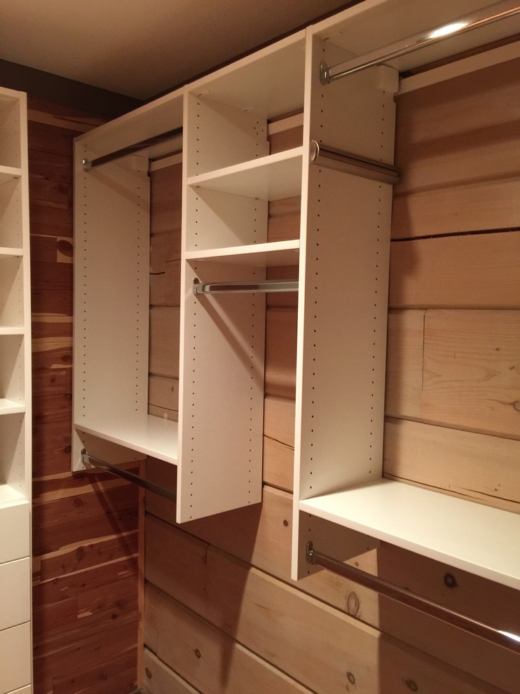 Photo of a mid-sized gender-neutral walk-in wardrobe in Charlotte with flat-panel cabinets, white cabinets and medium hardwood floors.