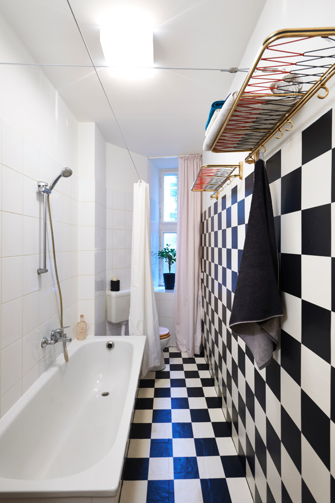 Inspiration for a mid-sized country 3/4 bathroom in Berlin with a drop-in tub, a one-piece toilet, white walls, linoleum floors, a console sink, black floor and a shower curtain.