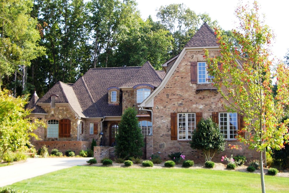 Inspiration for a large traditional two-storey brick brown exterior in Other with a clipped gable roof.