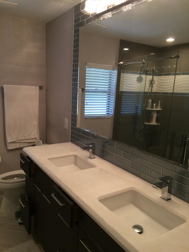 Example of a mid-sized trendy master blue tile and glass tile ceramic tile and gray floor bathroom design in Miami with an undermount sink, flat-panel cabinets, dark wood cabinets, granite countertops, a one-piece toilet and beige walls