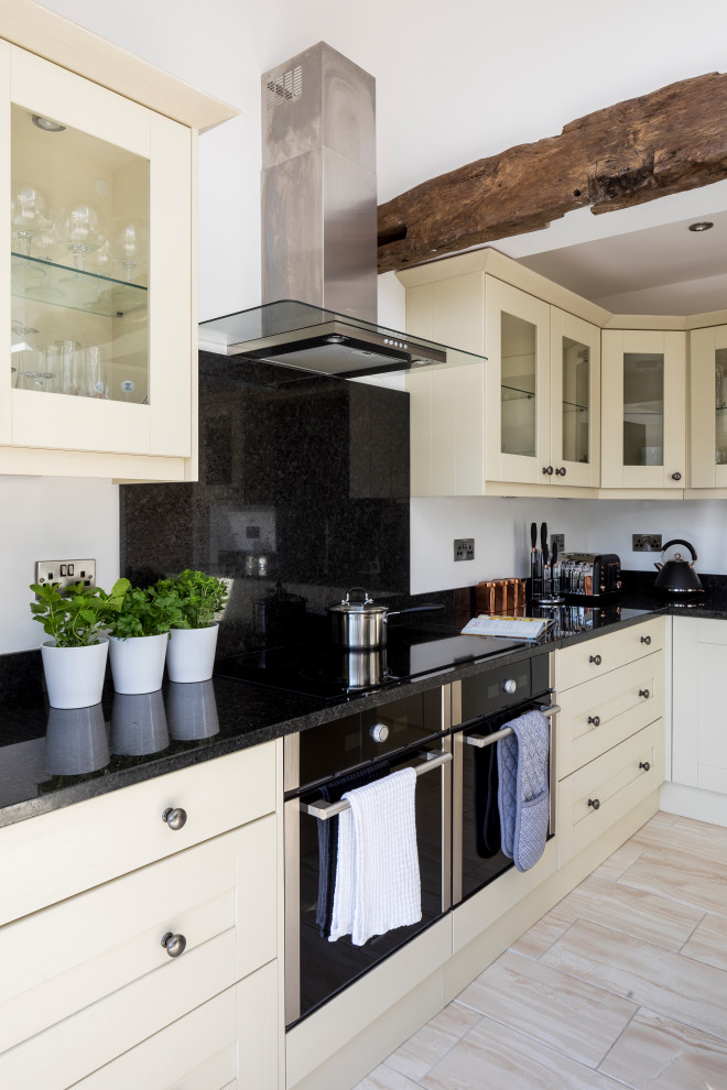 Design ideas for a large traditional cream and black l-shaped open plan kitchen in West Midlands with a double-bowl sink, glass-front cabinets, white cabinets, granite worktops, black splashback, laminate floors, an island, black worktops and exposed beams.
