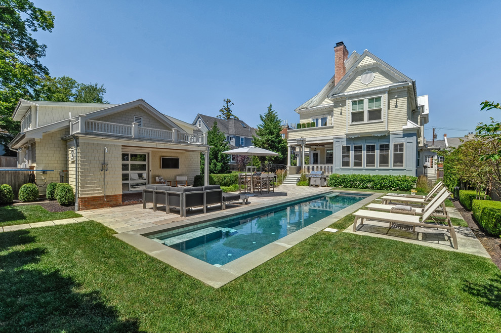 Photo of a traditional backyard rectangular lap pool in New York with a pool house and concrete pavers.
