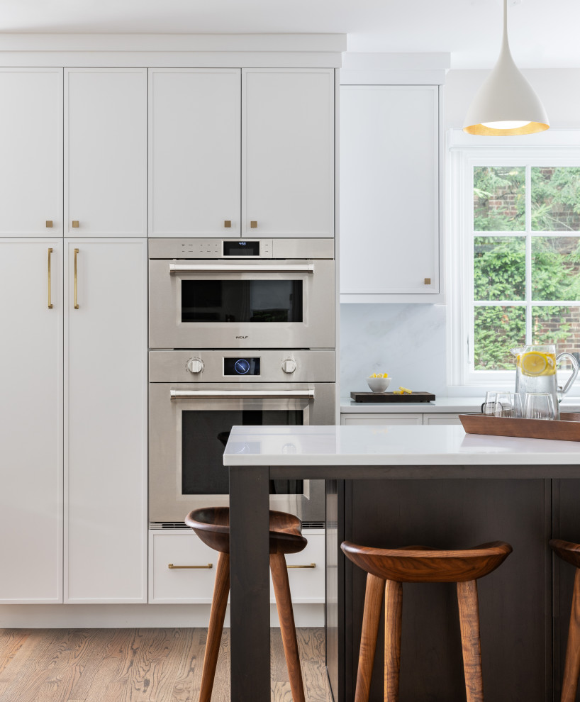 Inspiration for a large transitional medium tone wood floor and brown floor kitchen remodel with an undermount sink, shaker cabinets, white cabinets, quartz countertops, stainless steel appliances, an island and white countertops