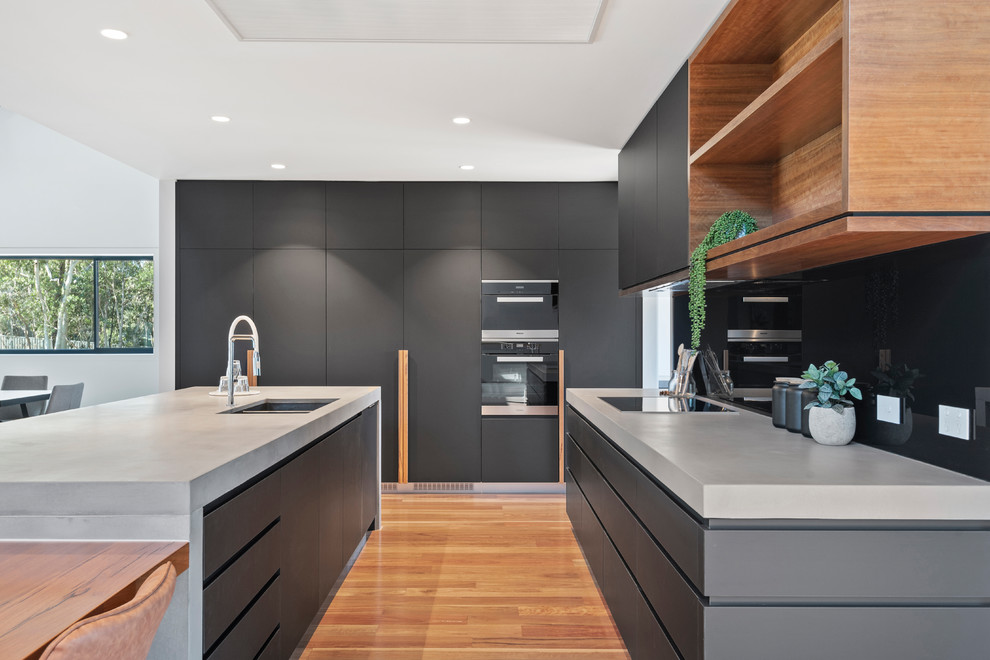 This is an example of a large contemporary galley eat-in kitchen in Brisbane with mirror splashback, medium hardwood floors, with island and grey benchtop.