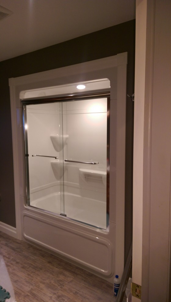 Mid-sized transitional master vinyl floor and multicolored floor alcove bathtub photo with recessed-panel cabinets, medium tone wood cabinets, a two-piece toilet, gray walls, laminate countertops and yellow countertops