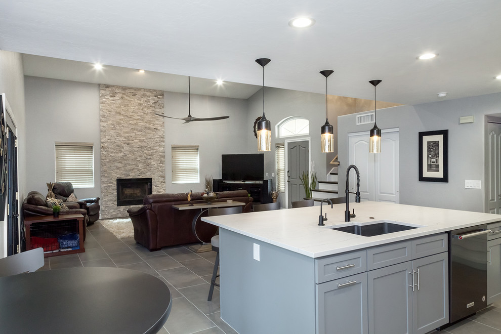 Inspiration for a mid-sized transitional l-shaped porcelain tile and gray floor open concept kitchen remodel in Phoenix with an undermount sink, shaker cabinets, white cabinets, quartz countertops, gray backsplash, glass tile backsplash, black appliances, an island and gray countertops