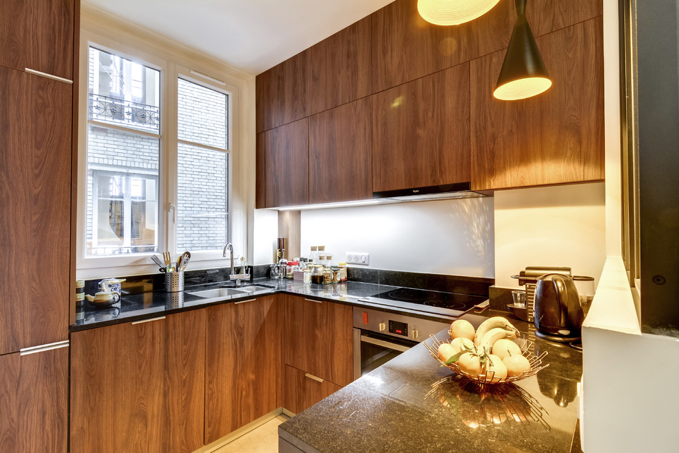 Small contemporary u-shaped open plan kitchen in Paris with an integrated sink, flat-panel cabinets, medium wood cabinets, granite benchtops, black splashback, stainless steel appliances, cement tiles, no island and grey floor.