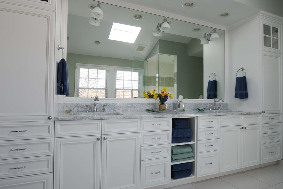 Inspiration for a mid-sized traditional bathroom in Chicago with an undermount sink, recessed-panel cabinets, white cabinets, white tile, a drop-in tub, an alcove shower, ceramic tile, grey walls and ceramic floors.