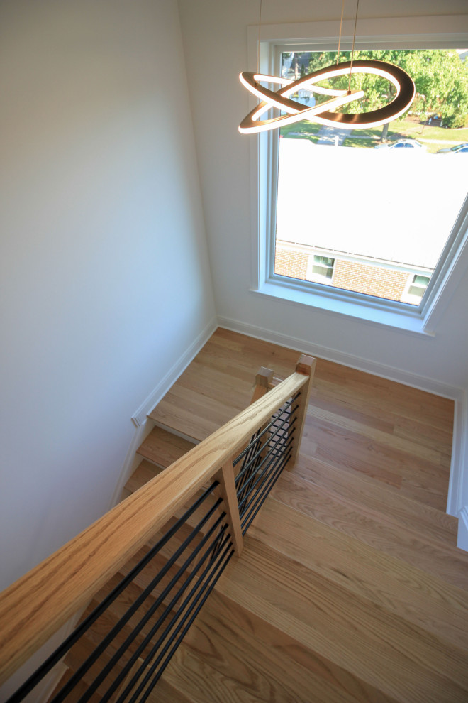 Cette image montre un escalier peint flottant design de taille moyenne avec des marches en bois, un garde-corps en matériaux mixtes et du lambris de bois.