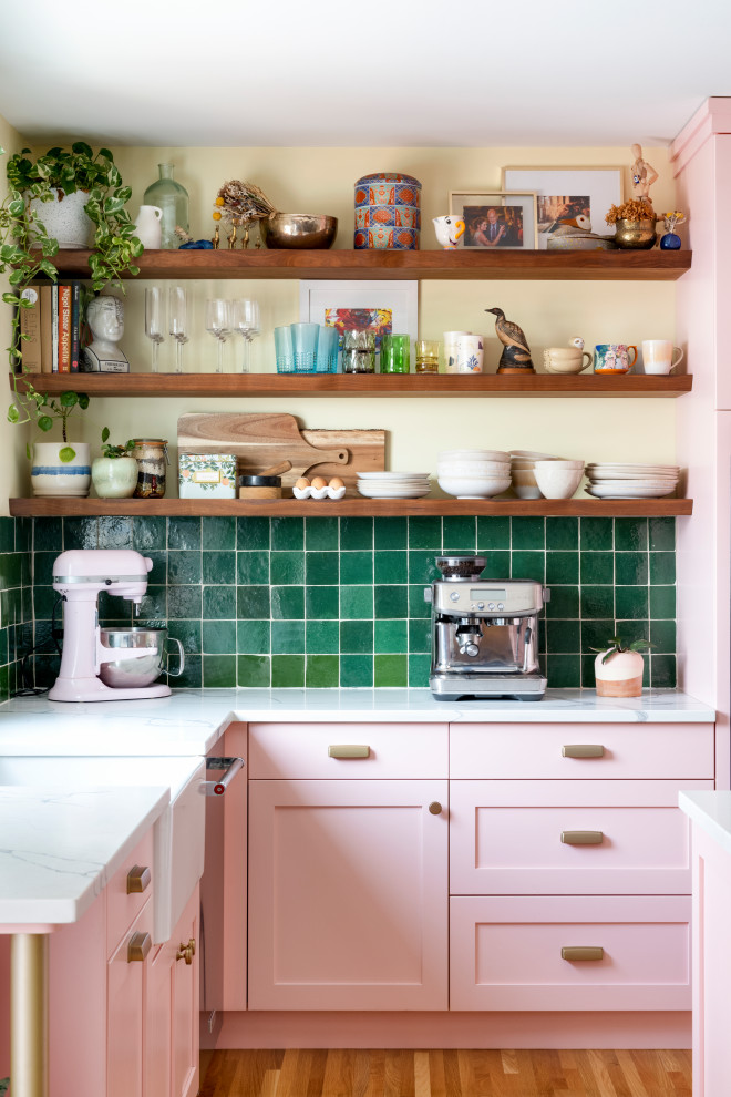 Mid-sized eclectic l-shaped eat-in kitchen in Minneapolis with a farmhouse sink, shaker cabinets, pink cabinets, quartz benchtops, green splashback, terra-cotta splashback, stainless steel appliances, light hardwood floors, with island, beige floor and white benchtop.