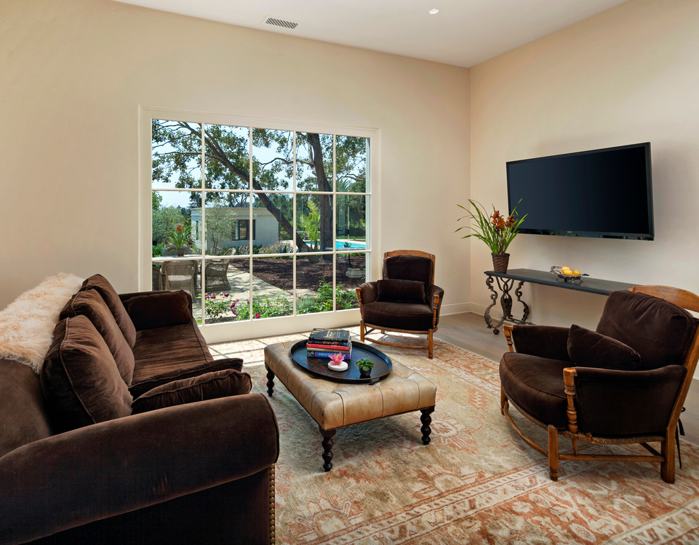 Photo of a mid-sized mediterranean enclosed living room in Santa Barbara with beige walls, light hardwood floors and a wall-mounted tv.