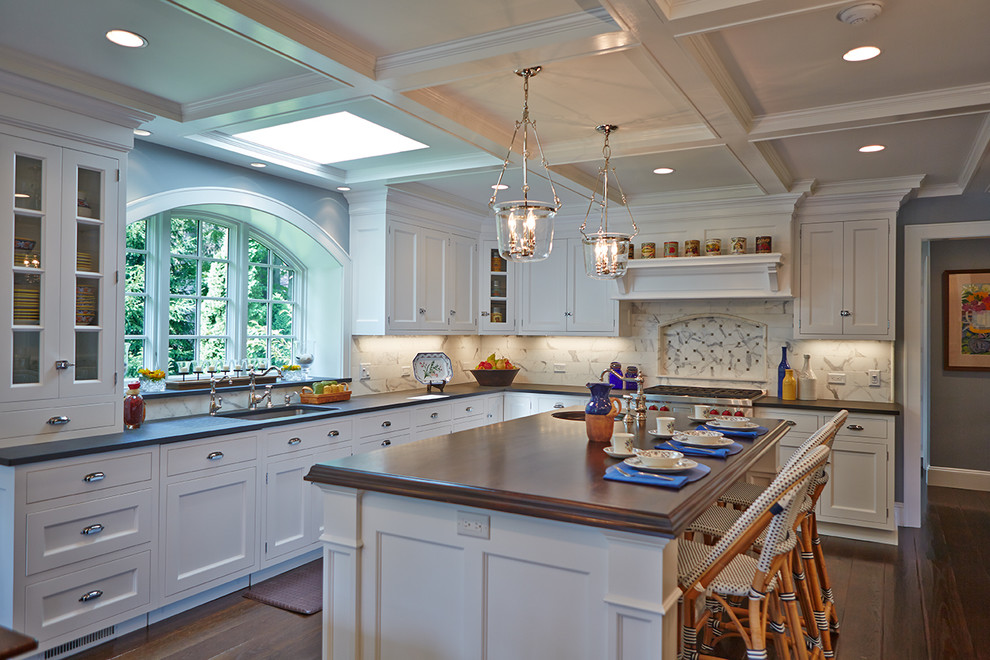 Design ideas for a mid-sized traditional l-shaped separate kitchen in New York with an undermount sink, shaker cabinets, white cabinets, white splashback, stainless steel appliances, stone tile splashback, wood benchtops, medium hardwood floors, with island and brown floor.