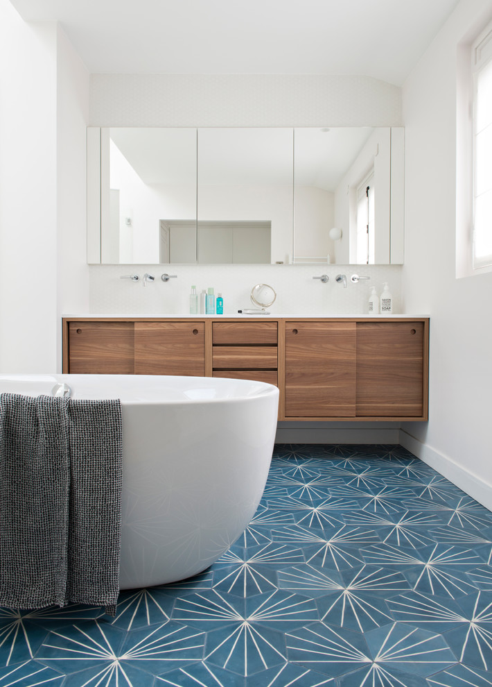 Design ideas for a contemporary bathroom in Paris with flat-panel cabinets, medium wood cabinets, a freestanding tub, white tile, mosaic tile, white walls, blue floor and white benchtops.