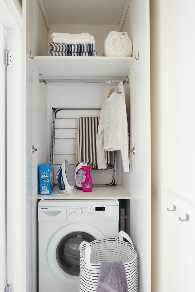 Inspiration for a small scandinavian single-wall laundry cupboard in Dublin with flat-panel cabinets, white cabinets, white walls, vinyl floors, an integrated washer and dryer and white floor.