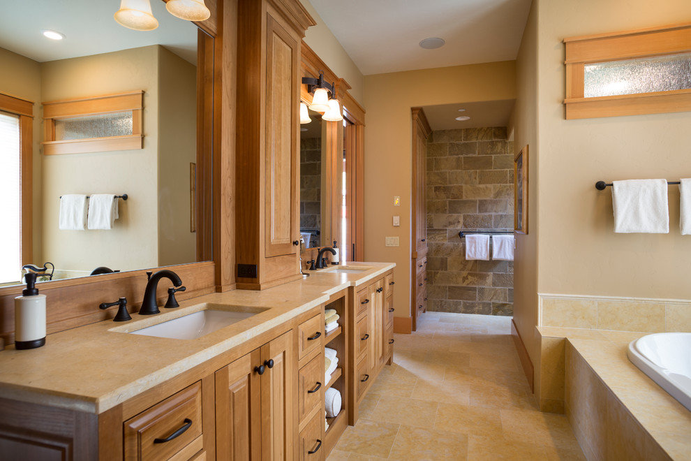 This is an example of an arts and crafts bathroom in Portland with raised-panel cabinets, medium wood cabinets, a drop-in tub, brown tile, beige walls, an undermount sink, beige floor and beige benchtops.