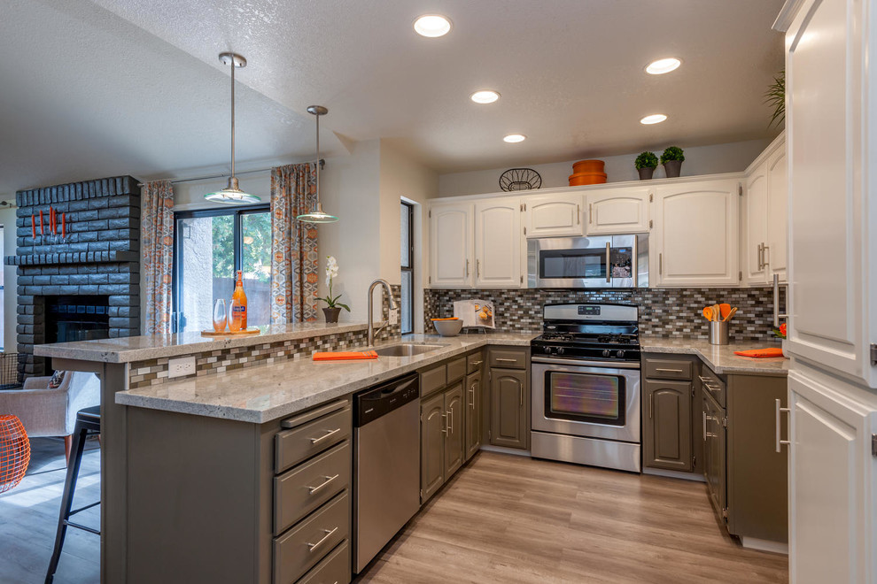 Open concept kitchen - mid-sized transitional u-shaped medium tone wood floor and brown floor open concept kitchen idea with an undermount sink, raised-panel cabinets, beige cabinets, granite countertops, multicolored backsplash, ceramic backsplash, stainless steel appliances, a peninsula and beige countertops