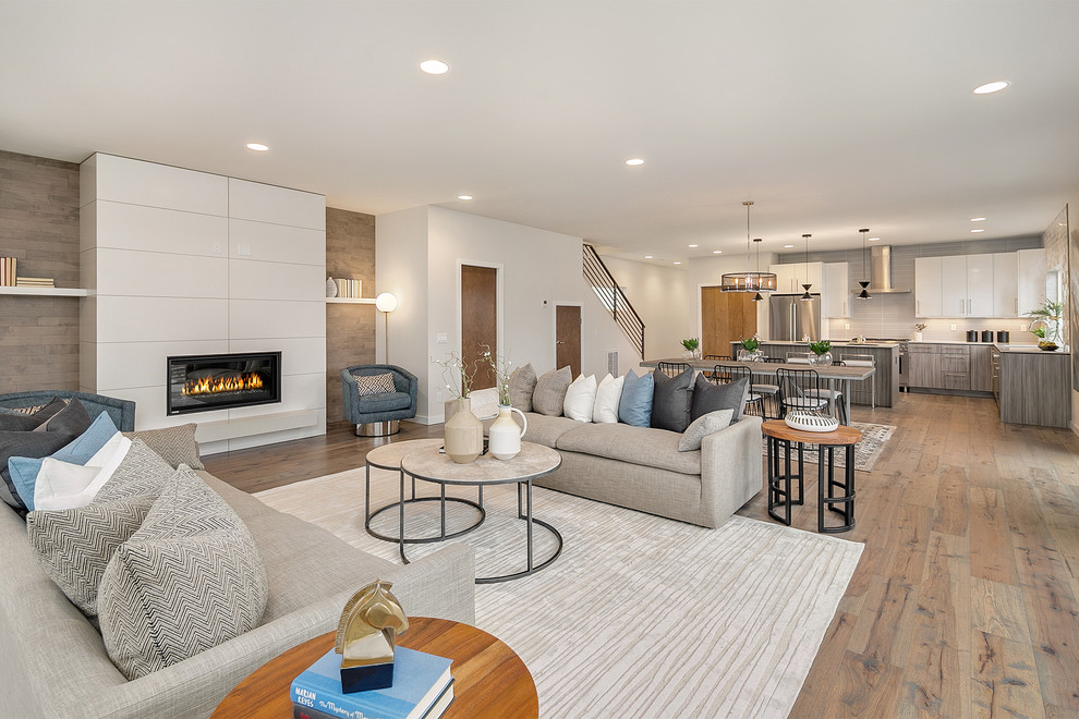 Design ideas for a contemporary open concept living room in Seattle with white walls, medium hardwood floors, a ribbon fireplace, a tile fireplace surround and brown floor.