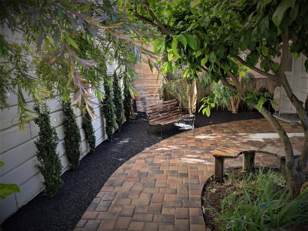 This is an example of a mid-sized and australian native asian backyard partial sun garden for spring in San Francisco with a garden path, concrete pavers and a wood fence.