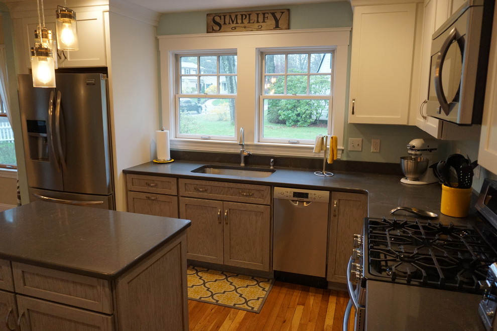 Inspiration for a mid-sized transitional u-shaped medium tone wood floor eat-in kitchen remodel in Boston with an undermount sink, shaker cabinets, gray cabinets, quartz countertops, black backsplash, stainless steel appliances and an island
