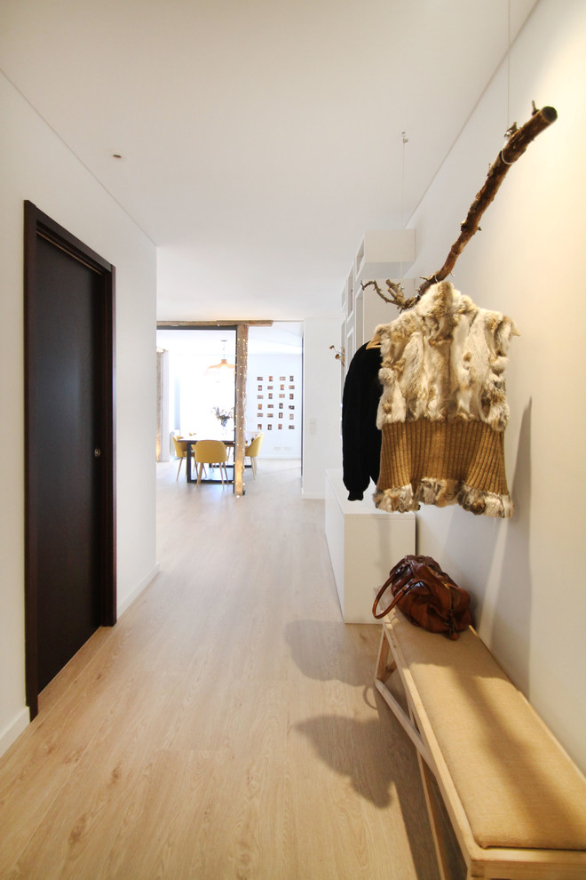 This is an example of a small contemporary foyer in Madrid with white walls, medium hardwood floors, a double front door and a dark wood front door.