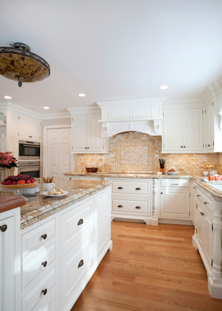 This is an example of a traditional l-shaped open plan kitchen in Bridgeport with raised-panel cabinets, white cabinets and panelled appliances.