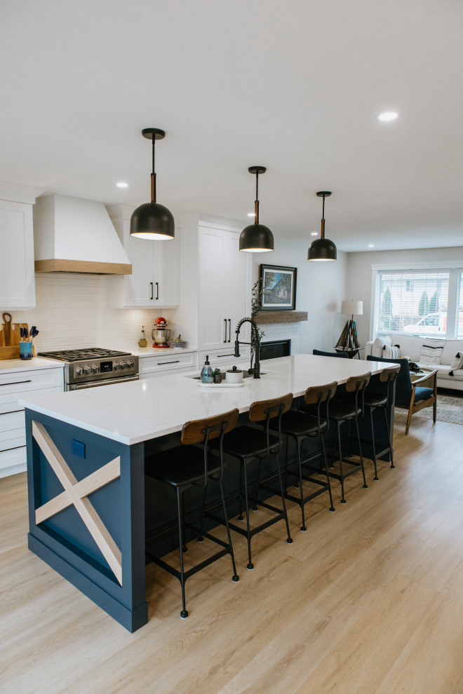 Inspiration for a country vinyl floor and brown floor kitchen remodel in Vancouver with recessed-panel cabinets, white cabinets, white backsplash, ceramic backsplash, stainless steel appliances, an island, white countertops and an undermount sink