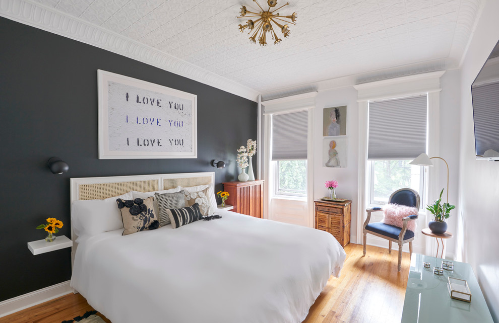 Design ideas for a mid-sized transitional master bedroom in New York with black walls, light hardwood floors and no fireplace.