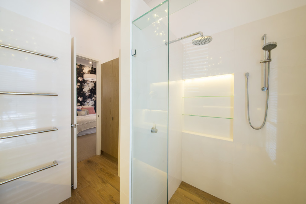 Inspiration for an expansive beach style 3/4 bathroom in Melbourne with flat-panel cabinets, white cabinets, a double shower, a one-piece toilet, white tile, ceramic tile, white walls, porcelain floors, an undermount sink, engineered quartz benchtops, brown floor and a hinged shower door.