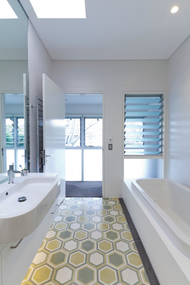 Inspiration for a small contemporary bathroom in Sydney with flat-panel cabinets, white cabinets, an alcove tub, white walls, ceramic floors, a wall-mount sink and green floor.