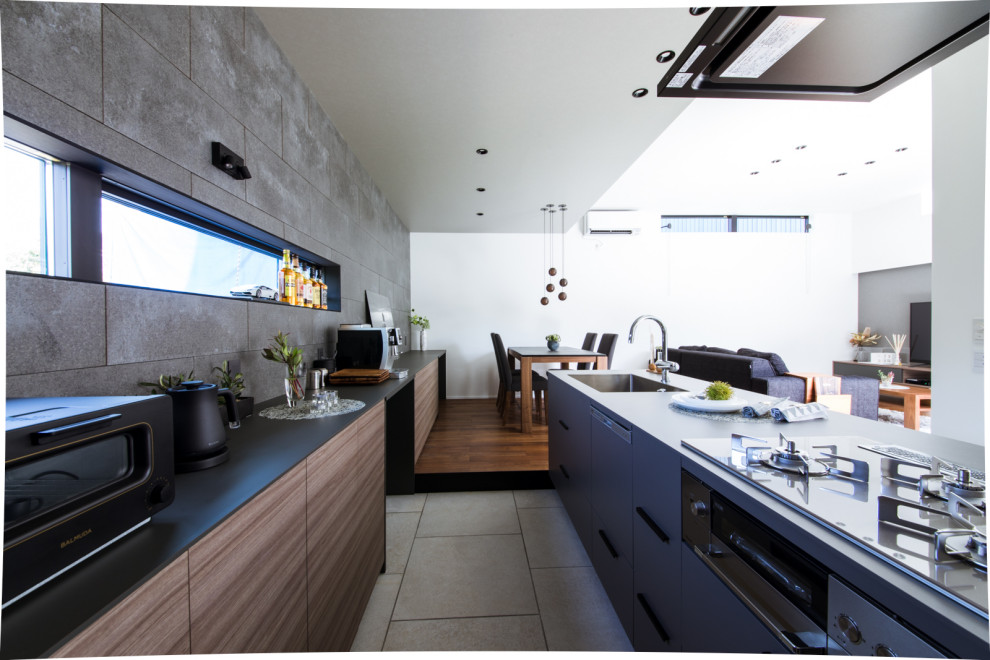 This is an example of a mid-sized contemporary galley open plan kitchen in Other with an integrated sink, flat-panel cabinets, dark wood cabinets, grey splashback, ceramic splashback, black appliances, porcelain floors, with island, grey floor, black benchtop and wallpaper.