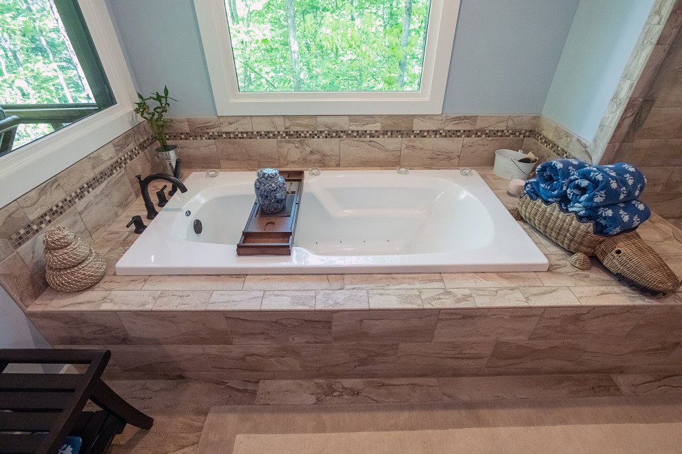 This is an example of a large transitional master bathroom in Atlanta with recessed-panel cabinets, medium wood cabinets, a drop-in tub, an alcove shower, a two-piece toilet, beige tile, porcelain tile, blue walls, porcelain floors, an undermount sink, granite benchtops, beige floor, a hinged shower door, brown benchtops, a shower seat, a double vanity and a built-in vanity.