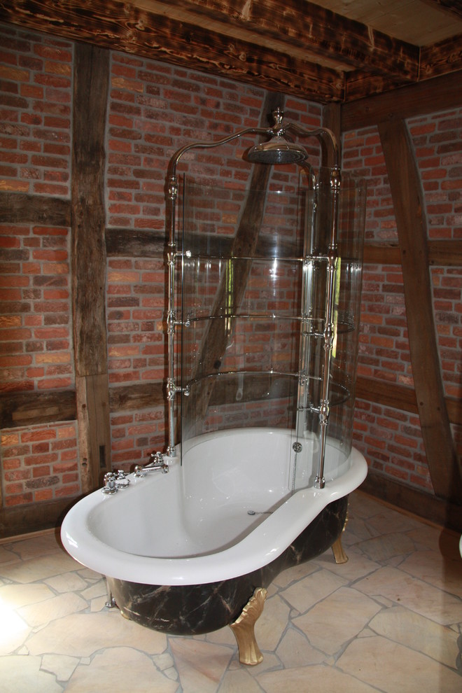 Foto på ett rustikt badrum, med ett badkar med tassar, röda väggar, klinkergolv i terrakotta och beiget golv