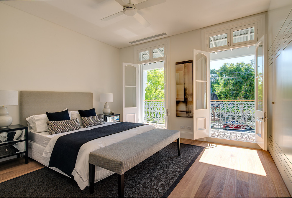 This is an example of a mid-sized transitional master bedroom in Sydney with light hardwood floors, no fireplace and white walls.