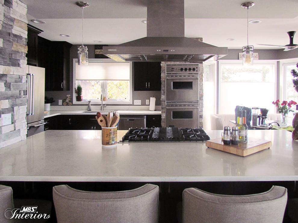 Example of a large transitional l-shaped light wood floor eat-in kitchen design with an undermount sink, recessed-panel cabinets, dark wood cabinets, quartz countertops, stainless steel appliances and an island