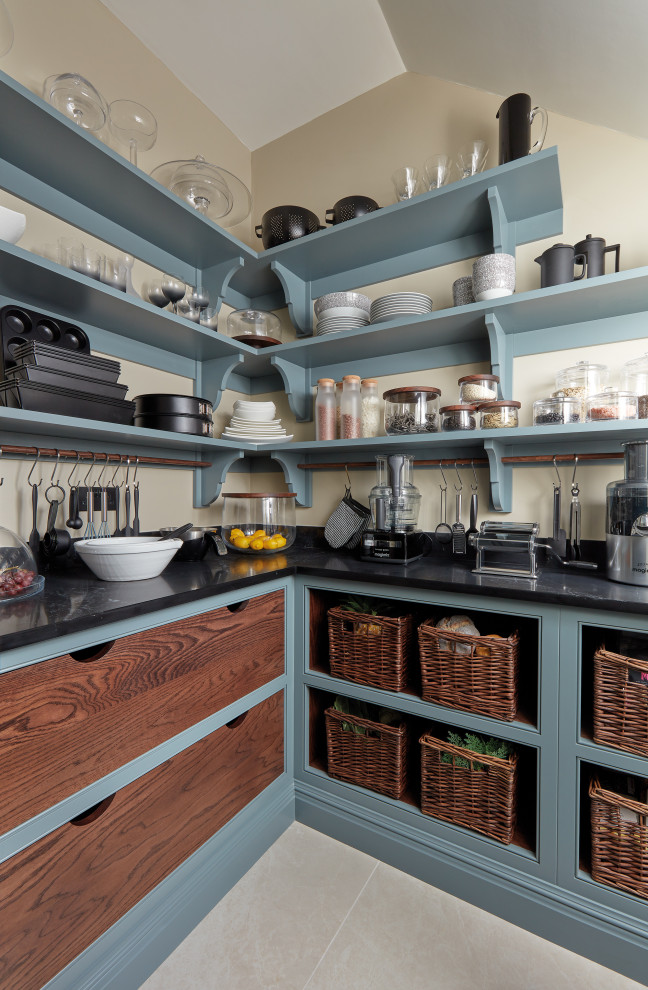 Klassisk inredning av ett avskilt, litet svart svart u-kök, med skåp i shakerstil, blå skåp och bänkskiva i kvartsit