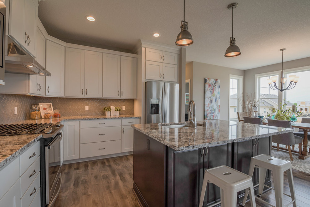 Eat-in kitchen - mid-sized transitional l-shaped medium tone wood floor and brown floor eat-in kitchen idea in Minneapolis with an undermount sink, shaker cabinets, white cabinets, granite countertops, beige backsplash, ceramic backsplash, stainless steel appliances and an island