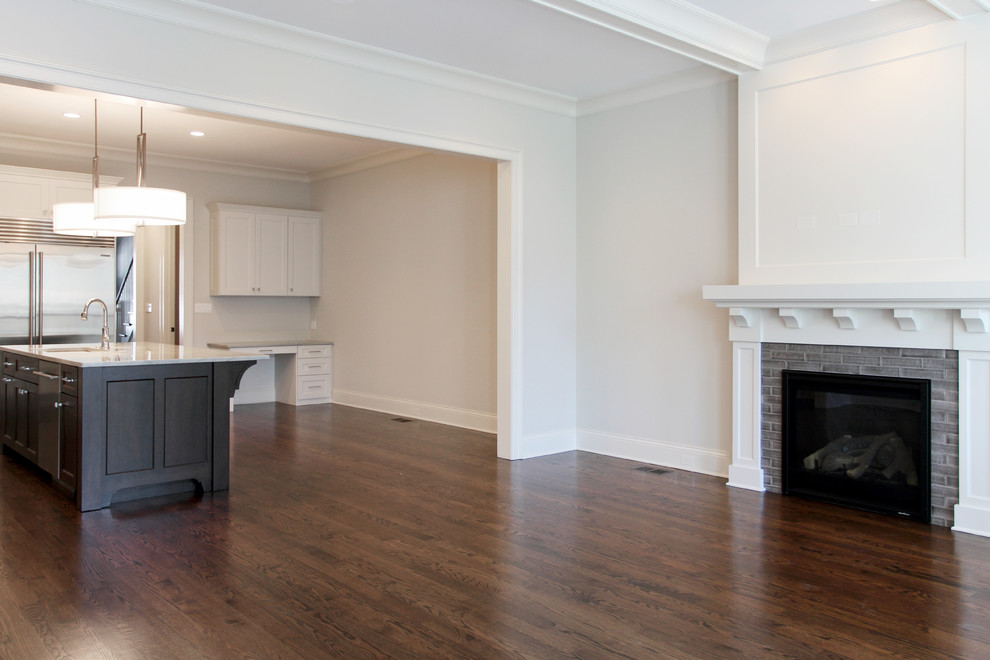 Photo of a mid-sized transitional open concept family room in Chicago with white walls, medium hardwood floors, a standard fireplace, a tile fireplace surround, brown floor and a wall-mounted tv.