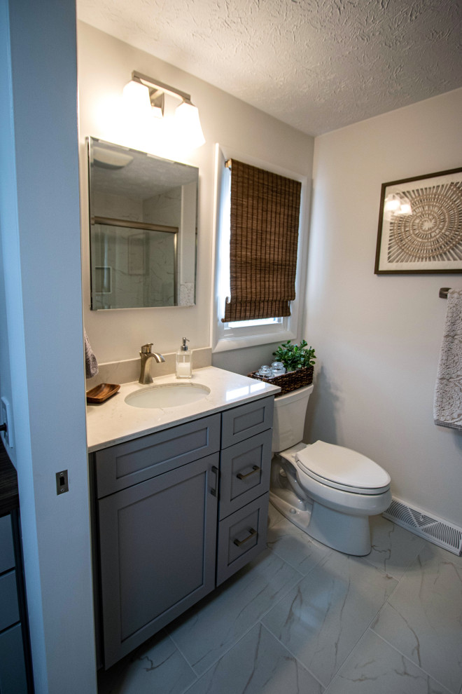 Idéer för att renovera ett litet vintage beige beige en-suite badrum, med släta luckor, grå skåp, en dusch i en alkov, en toalettstol med separat cisternkåpa, vit kakel, beige väggar, klinkergolv i keramik, bänkskiva i kvarts, vitt golv och dusch med skjutdörr