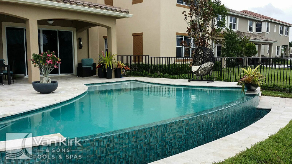 Design ideas for a mid-sized contemporary backyard custom-shaped infinity pool in Miami with a water feature and natural stone pavers.