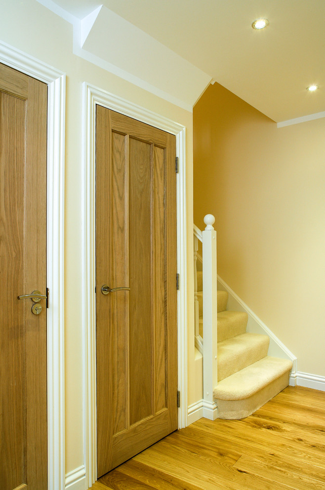 Photo of a small contemporary hallway in Kent with beige walls and light hardwood floors.