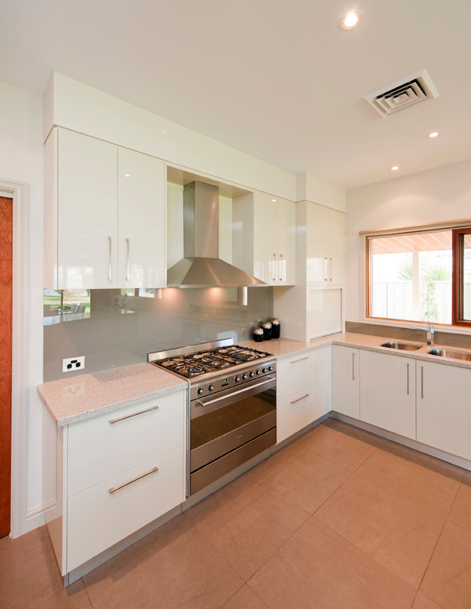 Large contemporary kitchen in Melbourne with an undermount sink, flat-panel cabinets, white cabinets, metallic splashback, glass sheet splashback, stainless steel appliances and with island.