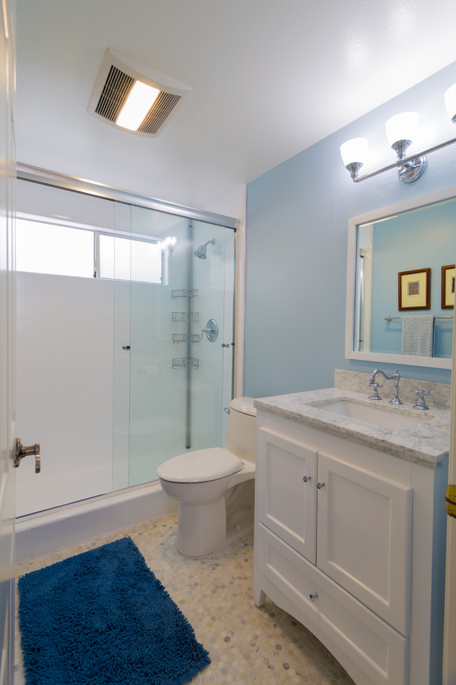This is an example of a small contemporary bathroom in Los Angeles with recessed-panel cabinets, white cabinets, an alcove shower, a one-piece toilet, blue walls, an undermount sink and marble benchtops.